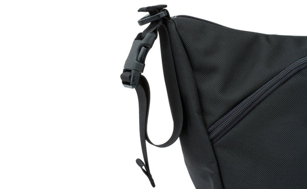 A close-up of a stroller/wheelchair adapter strap attached to the shoulder strap d-ring of a Parental Unit in Black 525 Ballistic.